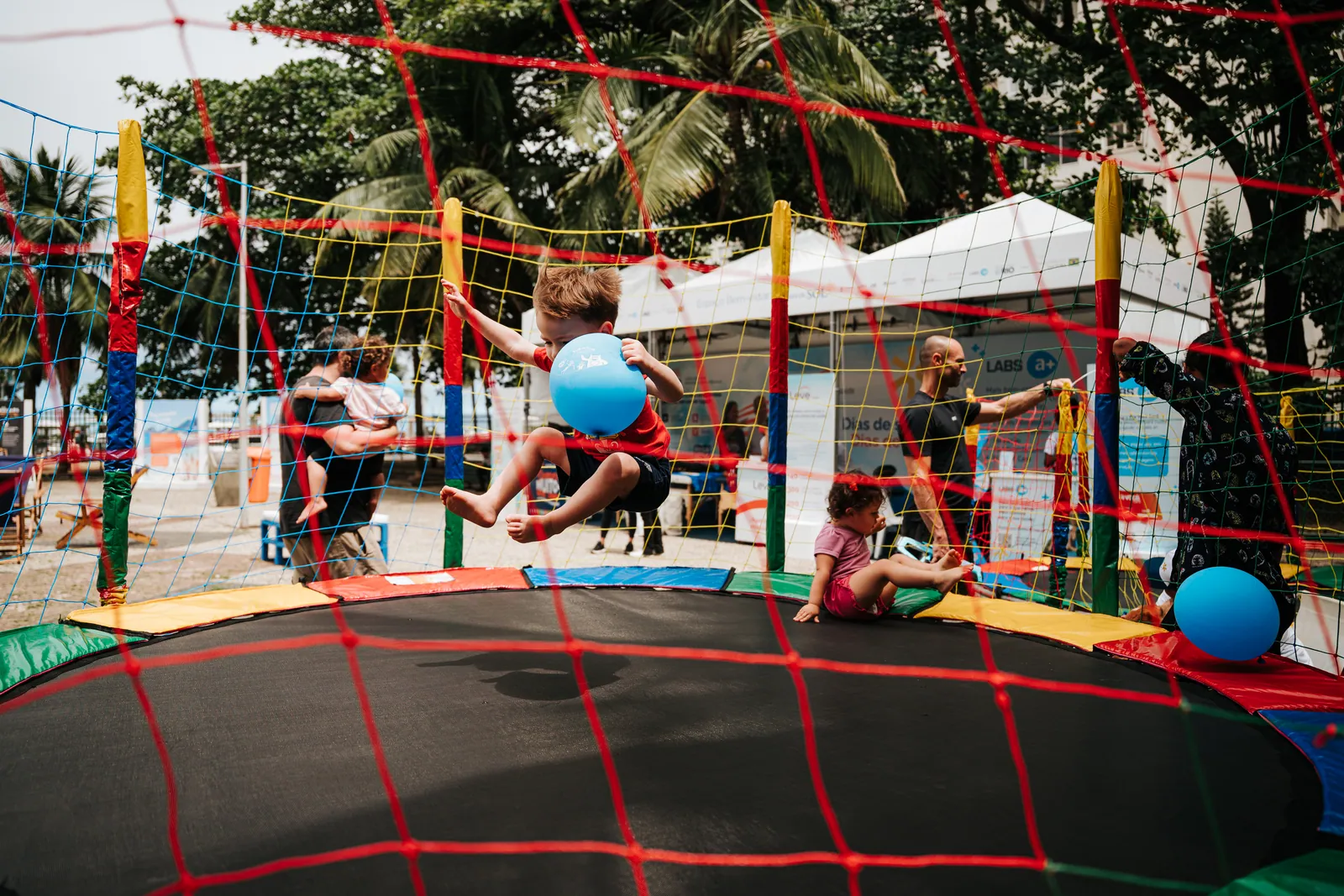Criança pula na cama elástica na área infantil do Festival Dias de Sol