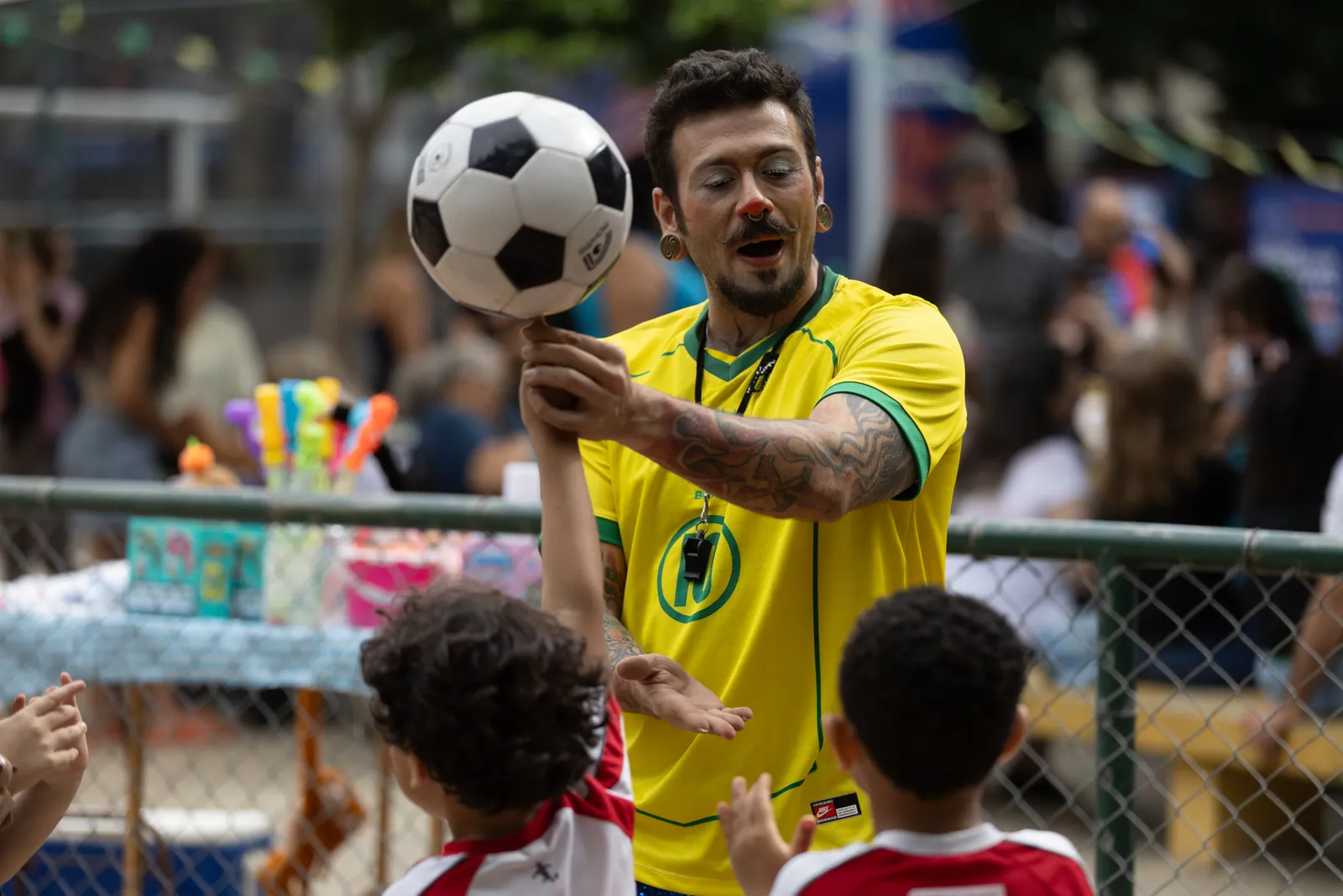 Artista de camisa da seleção equilibra bola de futebol na mão durante apresentação no Encontro Viva Bem