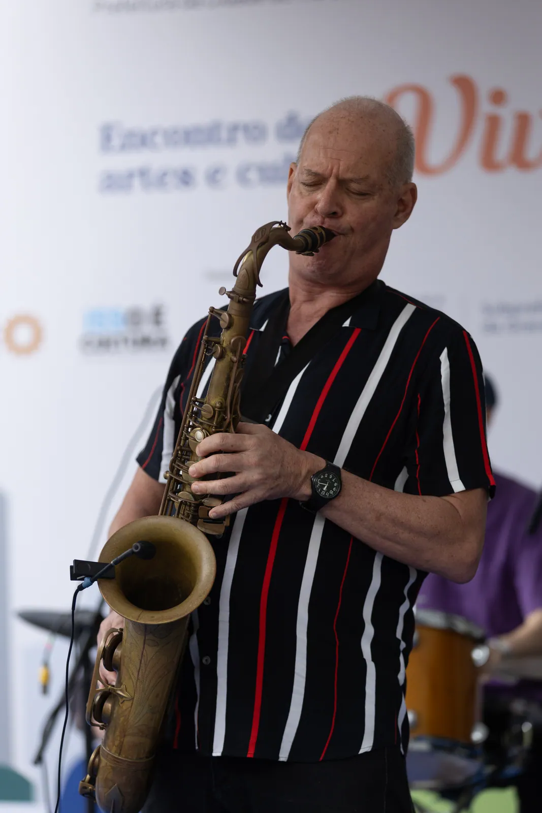 Saxofonista toca ao vivo diante do painel do Encontro de Artes e Cultura Viva Bem