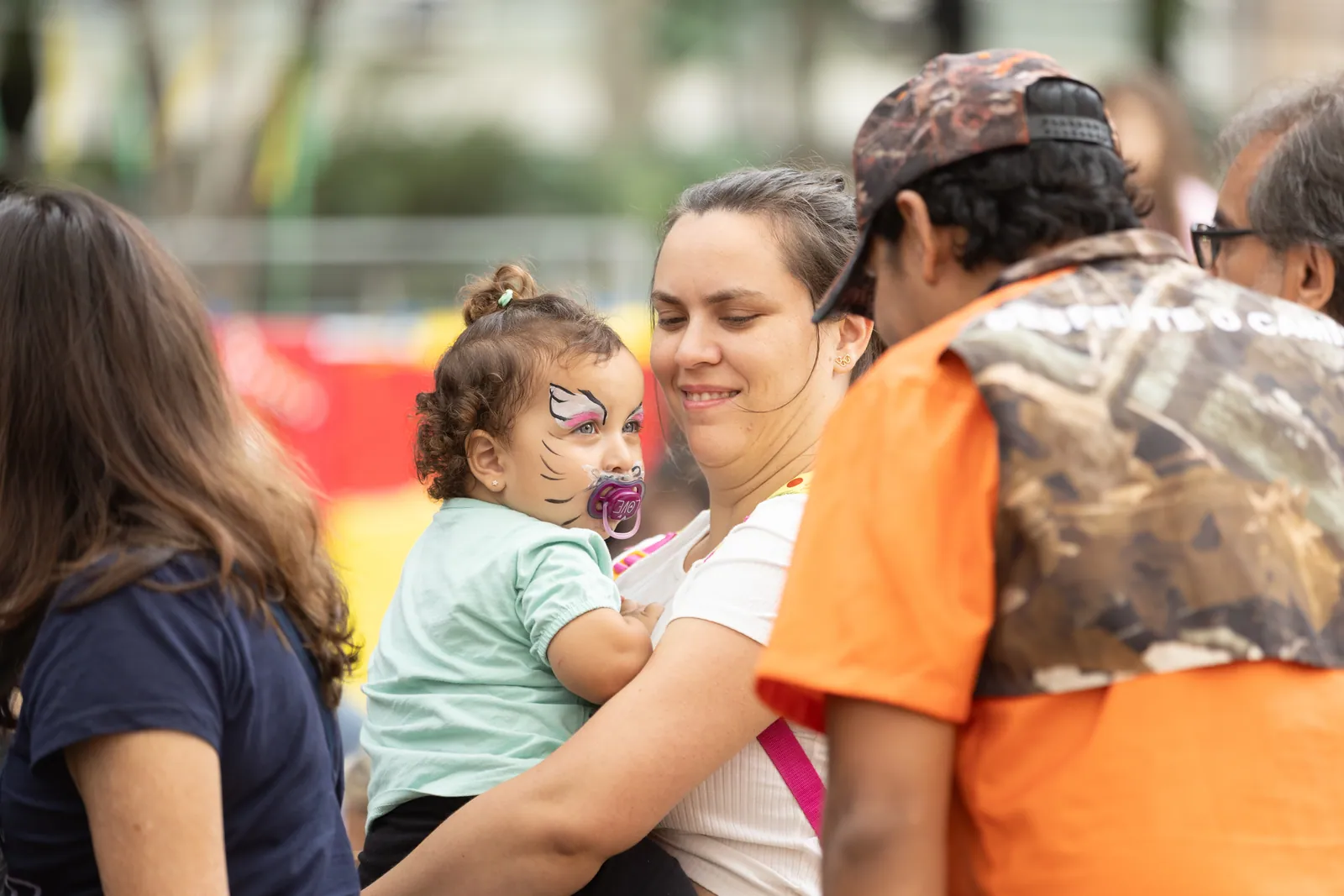 Bebê com pintura facial no colo da mãe durante o Encontro Viva Bem
