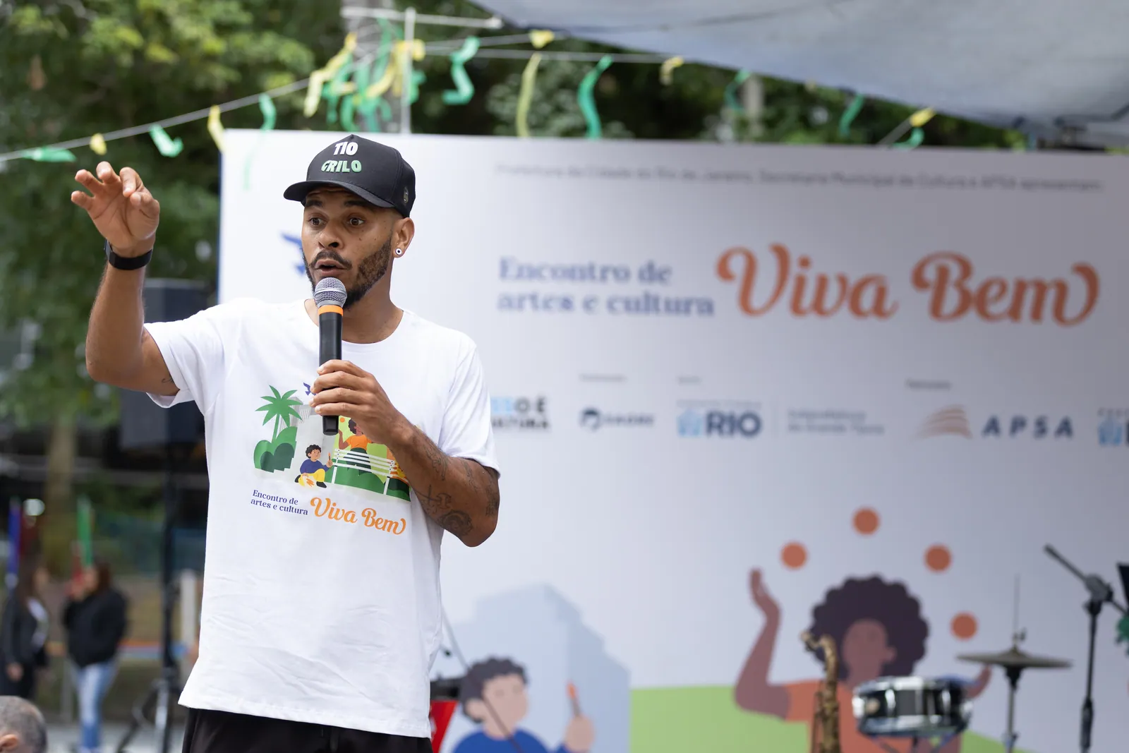 Apresentador de microfone em frente ao painel do Encontro de Artes e Cultura Viva Bem