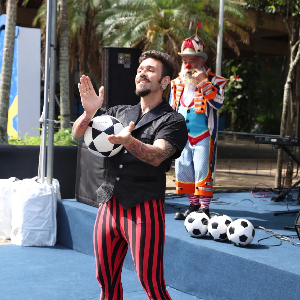 Artista equilibra bola de futebol na cabeça durante show circense em Copacabana