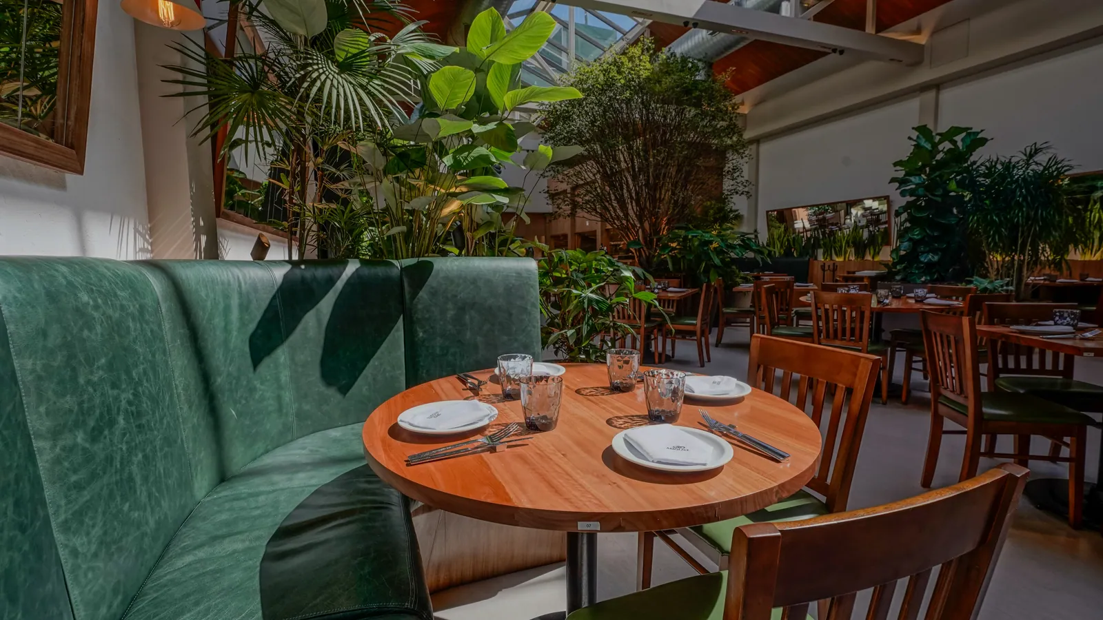 Mesa redonda posta entre plantas no restaurante São Miguel, em Botafogo
