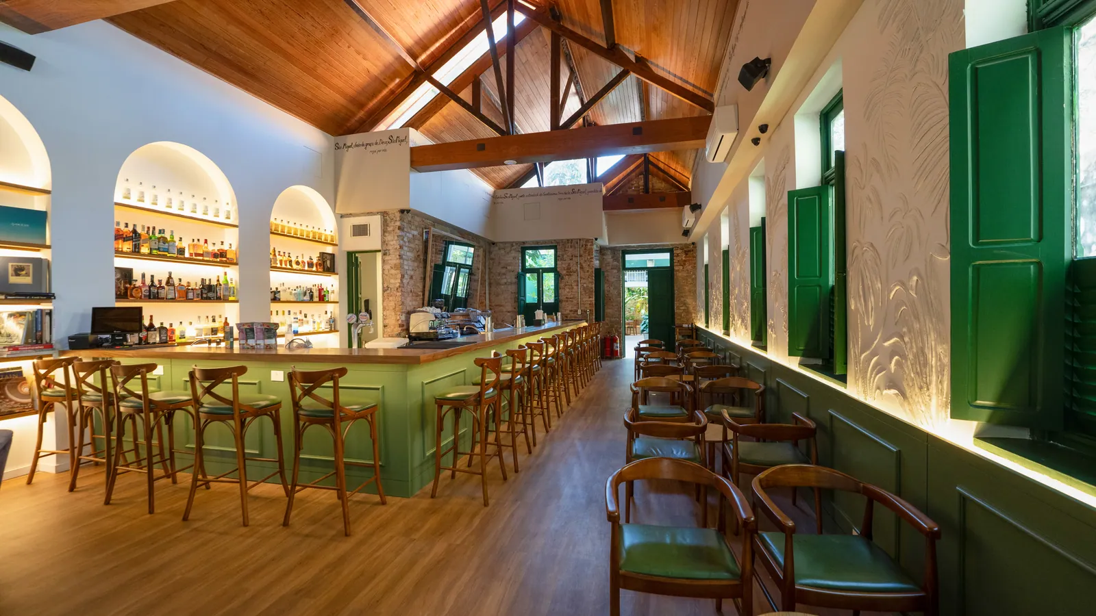 Bar verde com prateleiras em arcos e estrutura de madeira no restaurante São Miguel