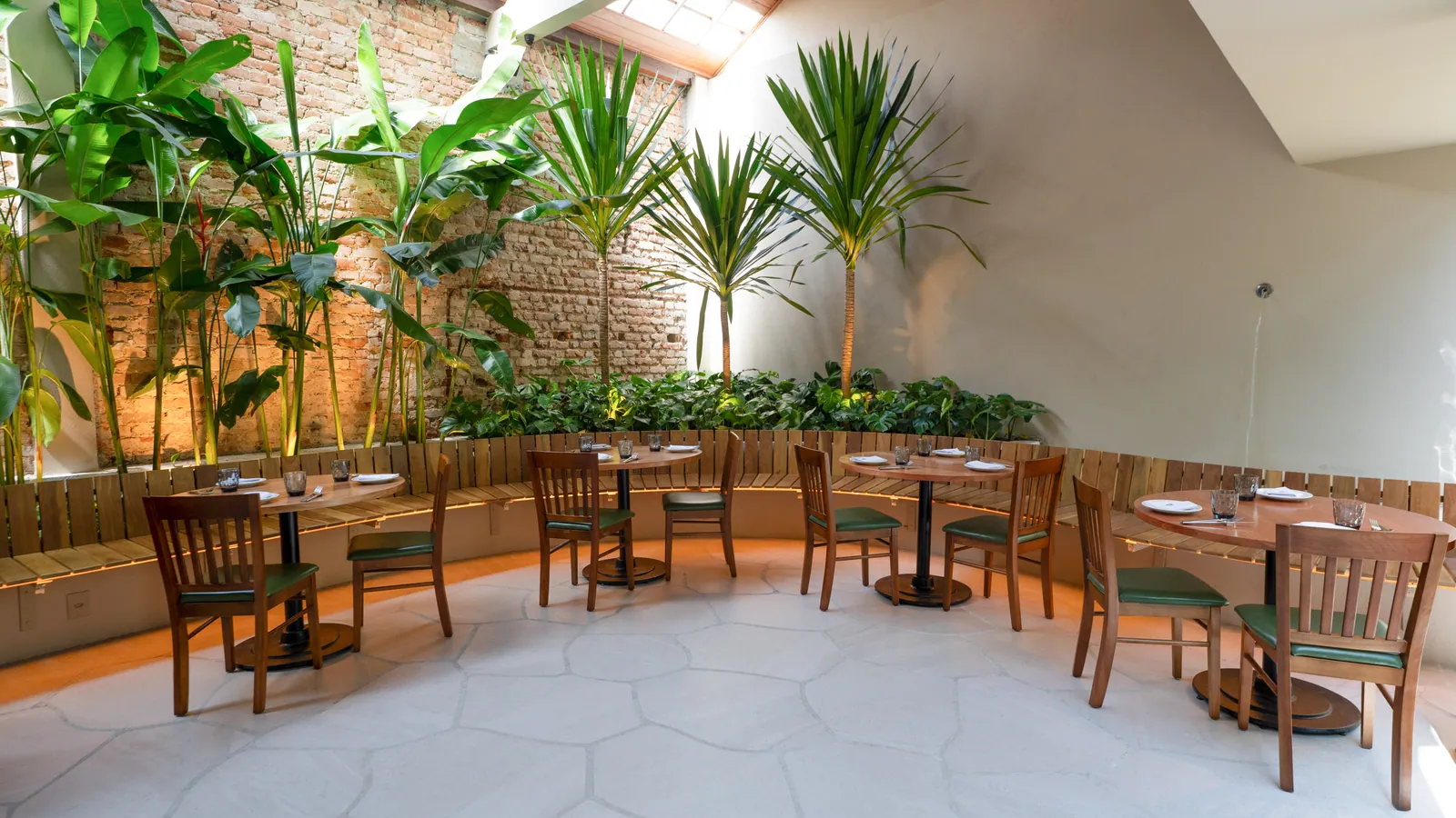Pátio interno com paredes de tijolo e jardim no restaurante São Miguel